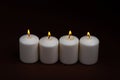 Four whiteÃÂ candlesÃÂ flameÃÂ burningÃÂ onÃÂ dark backgroundÃÂ withÃÂ copyÃÂ space forÃÂ text Royalty Free Stock Photo